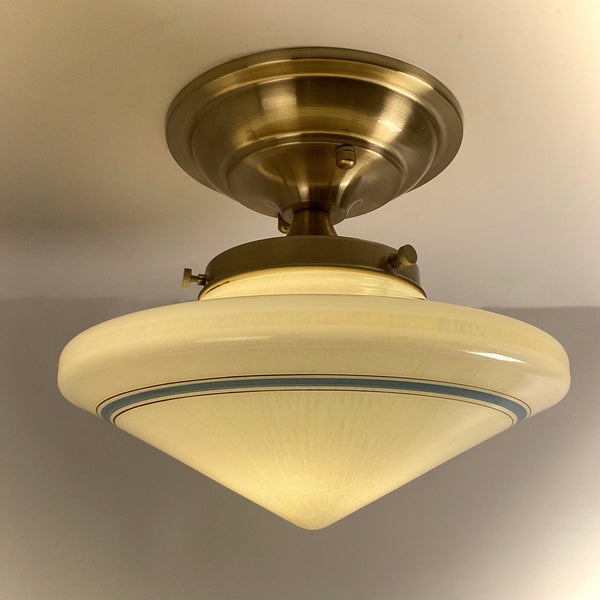 Up-close perspective view of the vintage light fixture emphasizing the clean satin brass finish and thumb screws securing the glass shade.