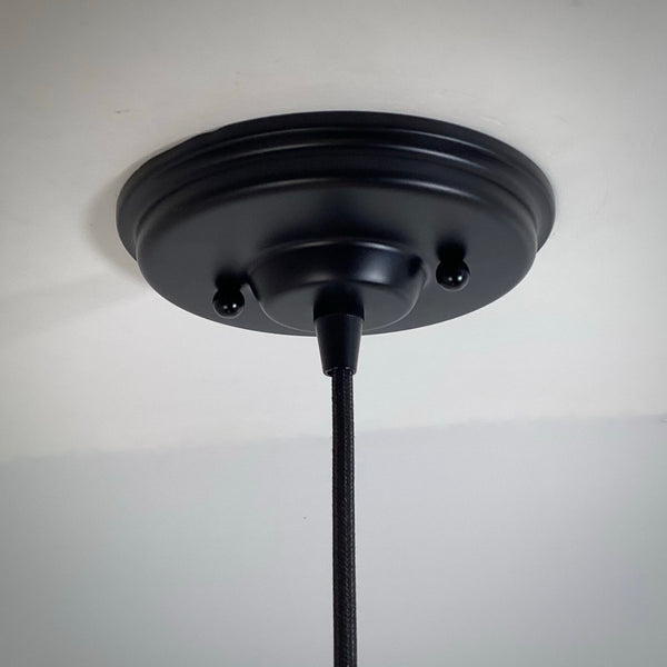 Close-up of a matte black round ceiling canopy for a pendant light fixture.