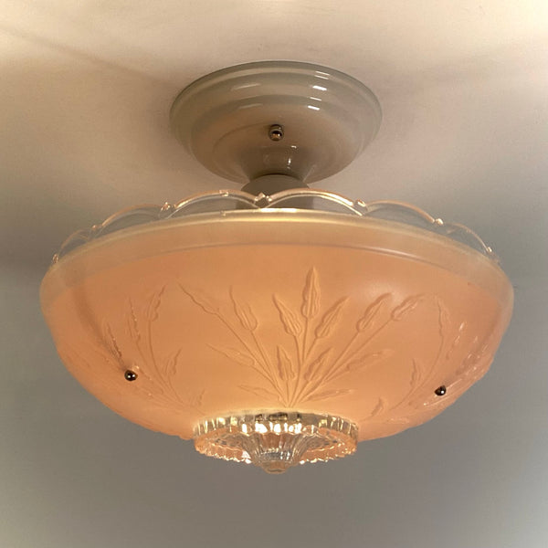 Warmly glowing pink frosted glass light shade with raised floral pattern and clear glass ribbed bottom accent.
