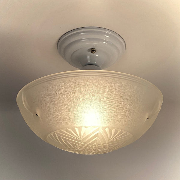 Illuminated 1930s powder-coated ceiling fixture with pressed-glass Art Deco shade showing a soft warm glow, available at Vintporium