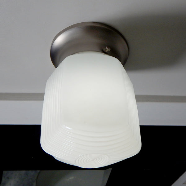 Detail of satin nickel wall canopy and pull-chain switch on vintage-inspired enameled glass fixture.