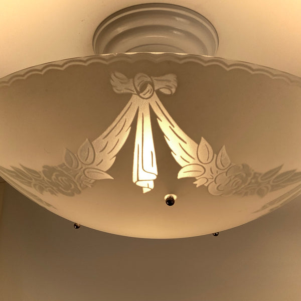 Close up of 1950s ceiling light glass bowl showing enameled ribbon swag and floral garland decoration
