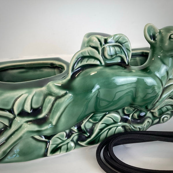 Close-up of the intricate leaf and forest floor texture at the base of the green ceramic deer planter.