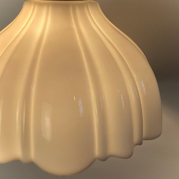 Extreme close-up of the ribbed texture and glossy finish of a milk glass lamp shade.