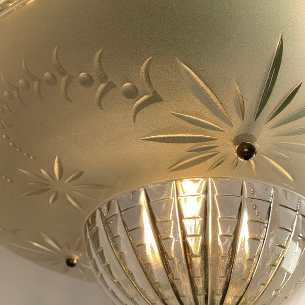 Detailed close-up of the intricate starburst etching and glowing clear glass dome on a vintage ceiling fixture.