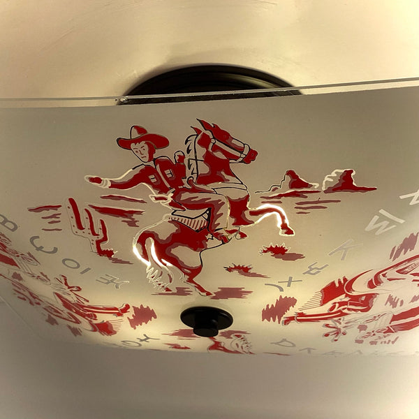 Macro photo highlighting the red cowboy riding a horse illustration on a vintage frosted glass light shade.