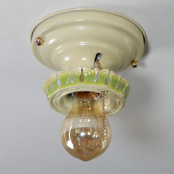 Vintage Ceiling Light Fixture With Pull Chain. The antique flush mount ceiling light fixture features charming ivory, green, and pink paint job and is topped with polished brass highlights. Even though the fixture has been cleaned and detailed, it still retains much of its aging and wear. It also includes the hardware for easy installation. Available at www.vintporium.com