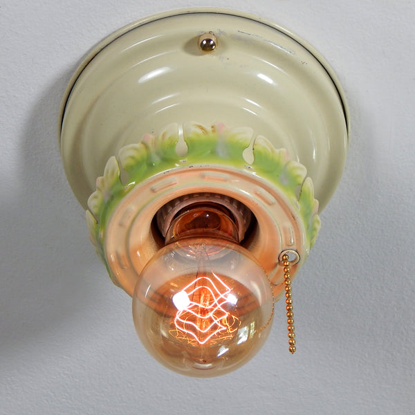 Vintage Ceiling Light Fixture With Pull Chain. The antique flush mount ceiling light fixture features charming ivory, green, and pink paint job and is topped with polished brass highlights. Even though the fixture has been cleaned and detailed, it still retains much of its aging and wear. It also includes the hardware for easy installation. Available at www.vintporium.com