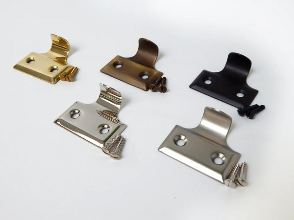 Angled view of traditional window sash lift handles showing multiple hardware finish options including brass, nickel, and bronze.