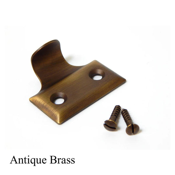 Antique brass sash lift handle for double-hung windows, traditional style cabinet pull with matching screws.