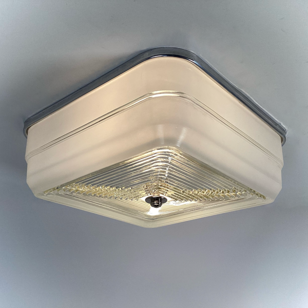 Vintage mid-century square flush mount ceiling light with aluminum fixture base and stepped glass diffuser, illuminated view — Vintporium