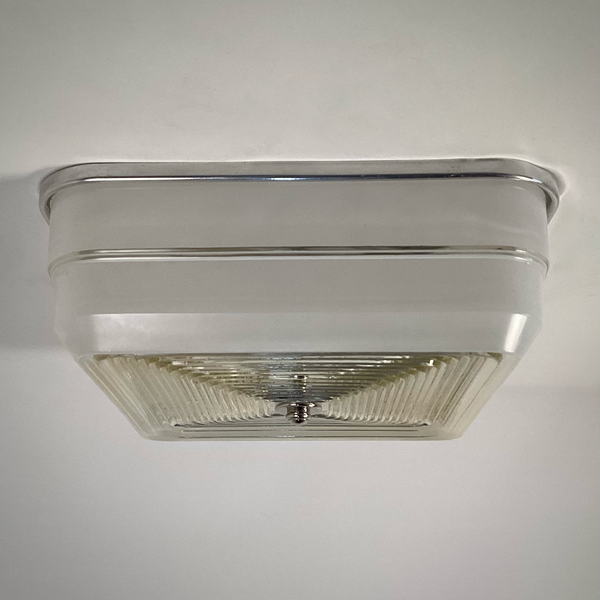 Close-up detail of mid-century square ceiling light with aluminum fixture base and concentric glass diffuser, illuminated view — Vintporium