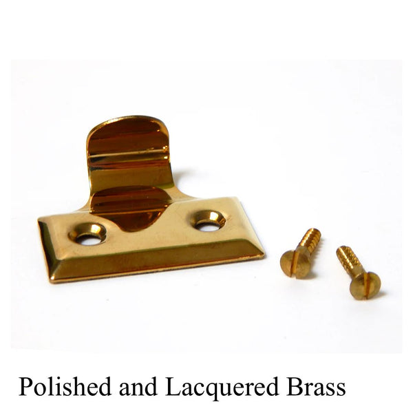 Polished and lacquered brass sash lift handle for double-hung windows with matching brass mounting screws.