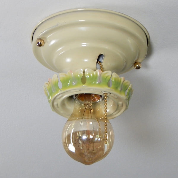The antique flush mount ceiling light fixture features charming ivory, green and pink paint job and is topped with polished brass highlights. Even though the fixture has been clean and detailed it still retains much of its aging and wear. It also includes the hardware for easy installation. Available at www.vintporium.com