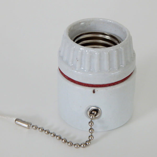 Medium base porcelain pull chain socket commonly found in vintage ceiling lights and sconces. The socket comes with a cloth cord extension and adjustable bead chain stop. Available at www.vintporium.com